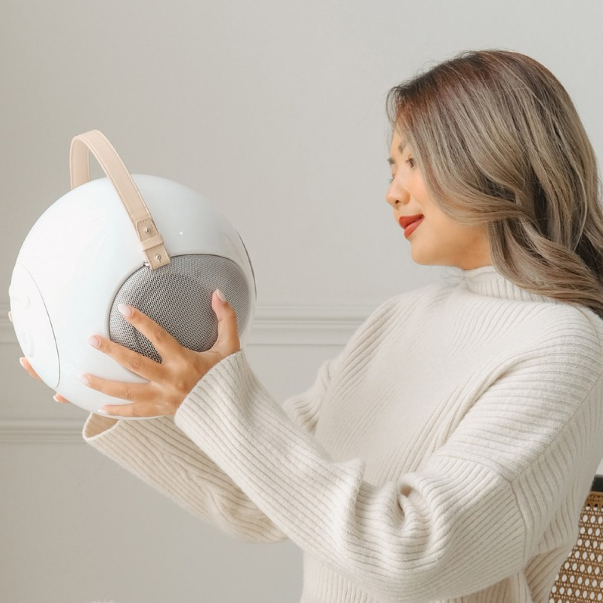 A girl holding the white S2+ ALPHORN UB+ Bluetooth Circle speaker at home showing that it's lightweight 
