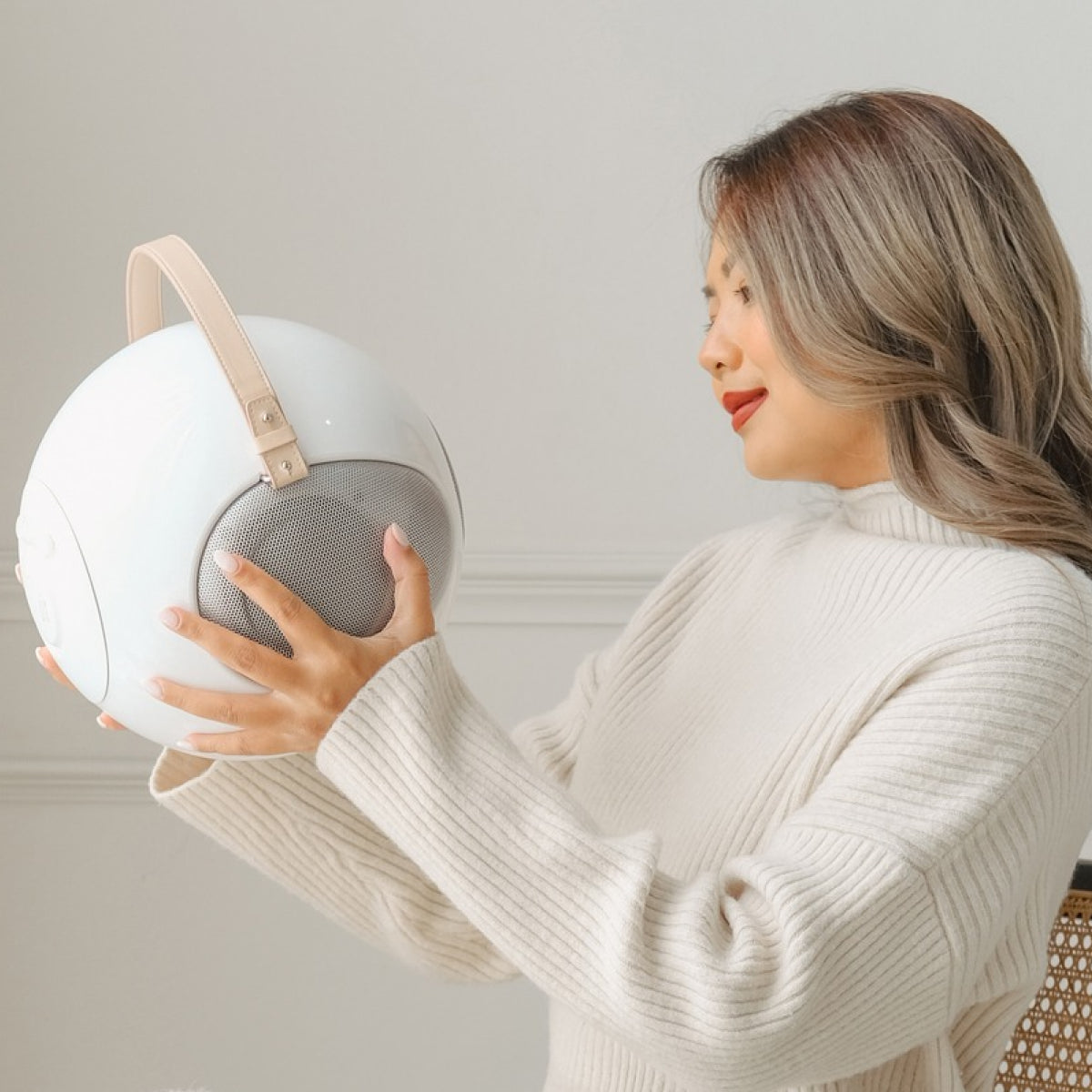 A girl holding the white S2+ ALPHORN UB+ Bluetooth Circle speaker at home showing that it's lightweight