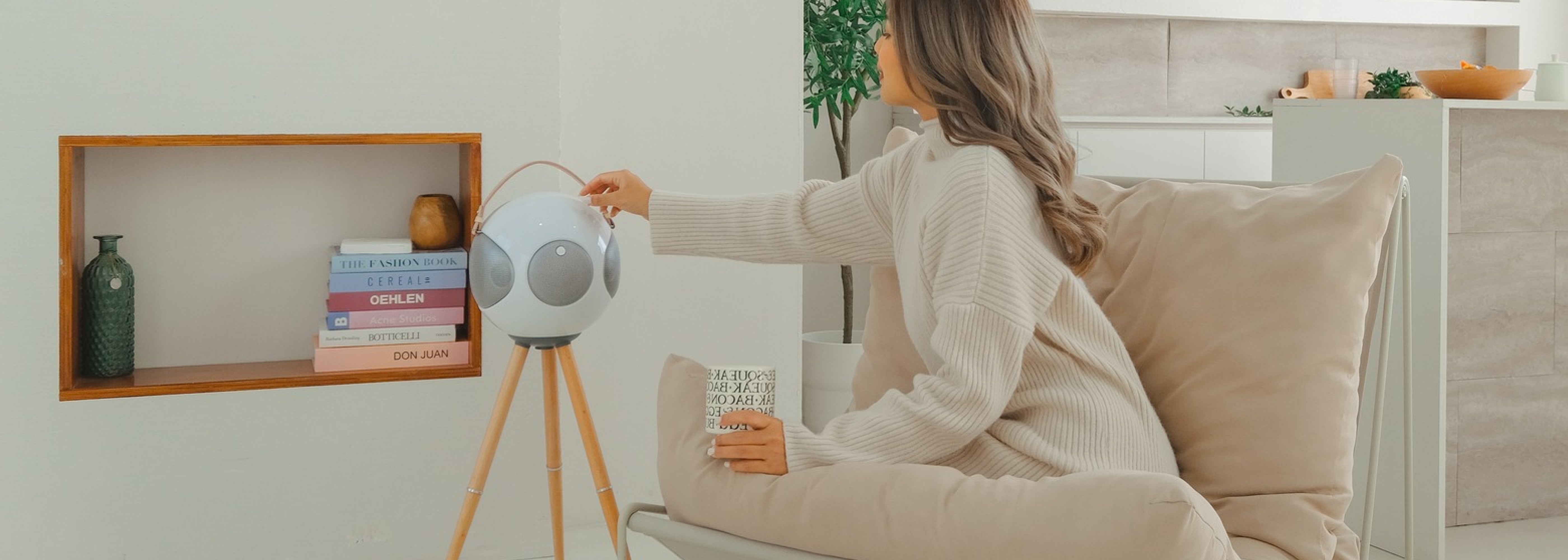 S2+ ALPHORN lifestyle photo. The speaker at home with a girl turning the speaker volume up